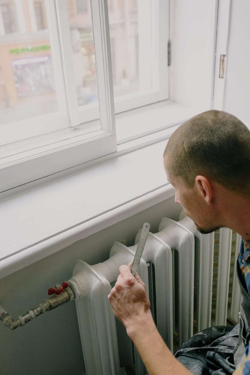unrecognizable handyman with ruler near heating system at home